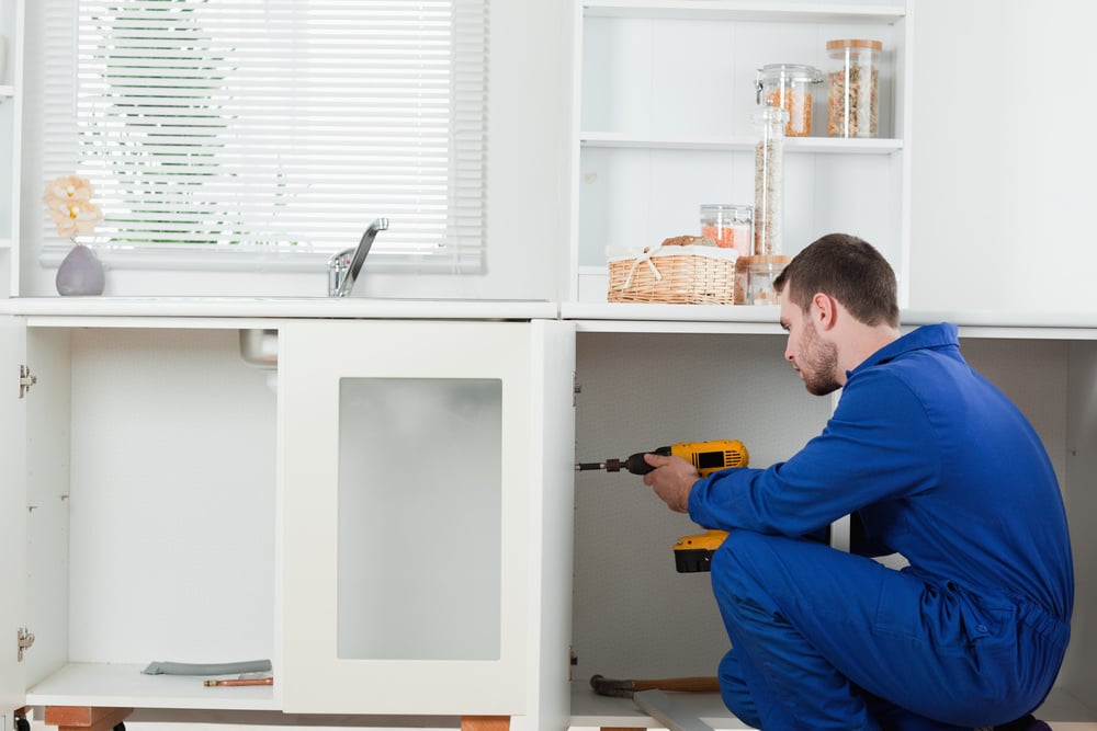 Good looking handyman fixing a door in a kitchen-1